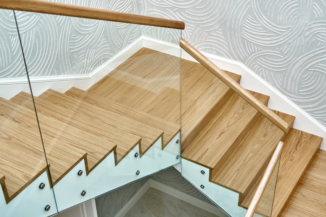 Wooden staircase with glass railings and wooden handrail